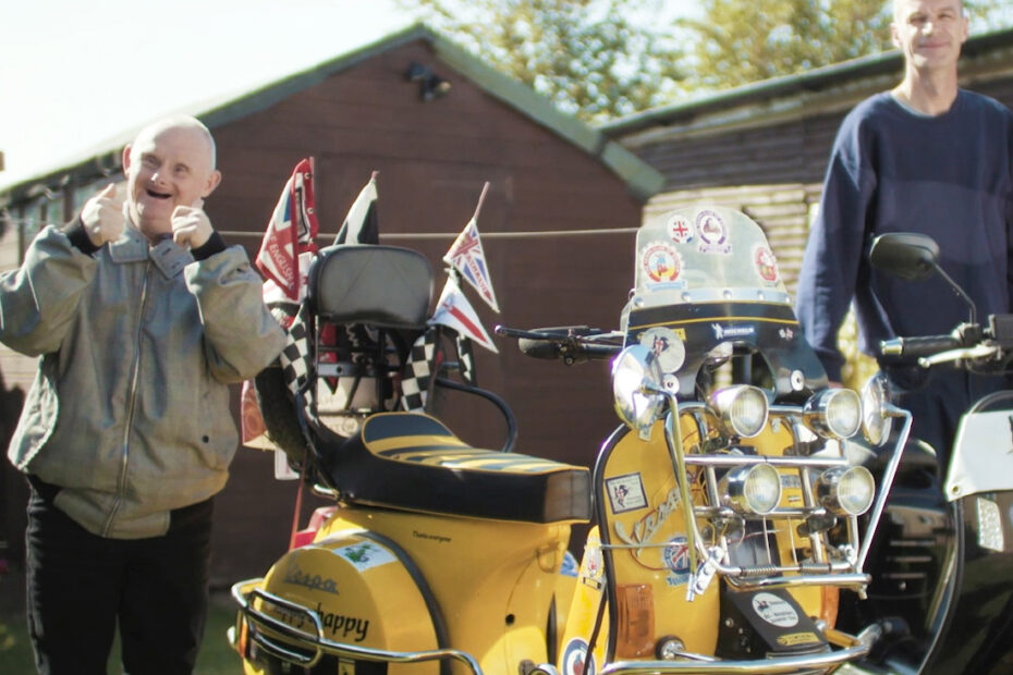Nicky smiling stood by a trike with thumbs up
