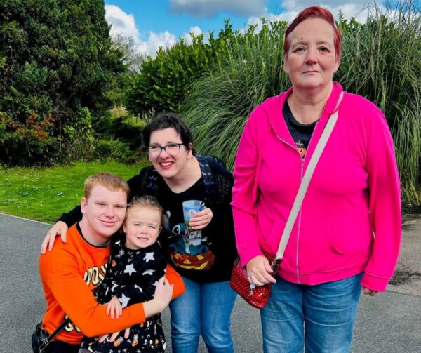 Pictured are the people Chloe supports with her daughter - they look just like family! Two women and one make stand around the daughter who smiles brightly and looks really comfortable with them - caregiving job with a difference.